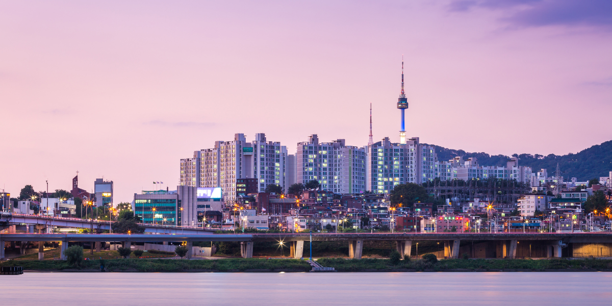 Seoul skyline at dusk with the mountains behind the city and the Han River in the foreground