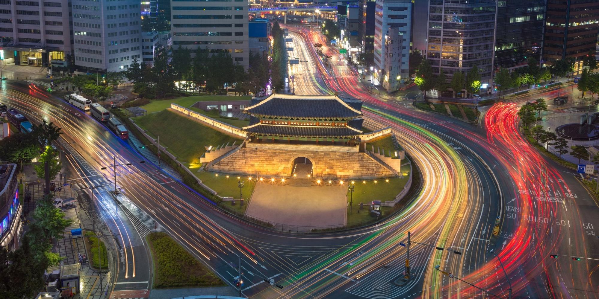 Namdaemun gate lit at night in Seoul, surrounded by traffic on the roads around it